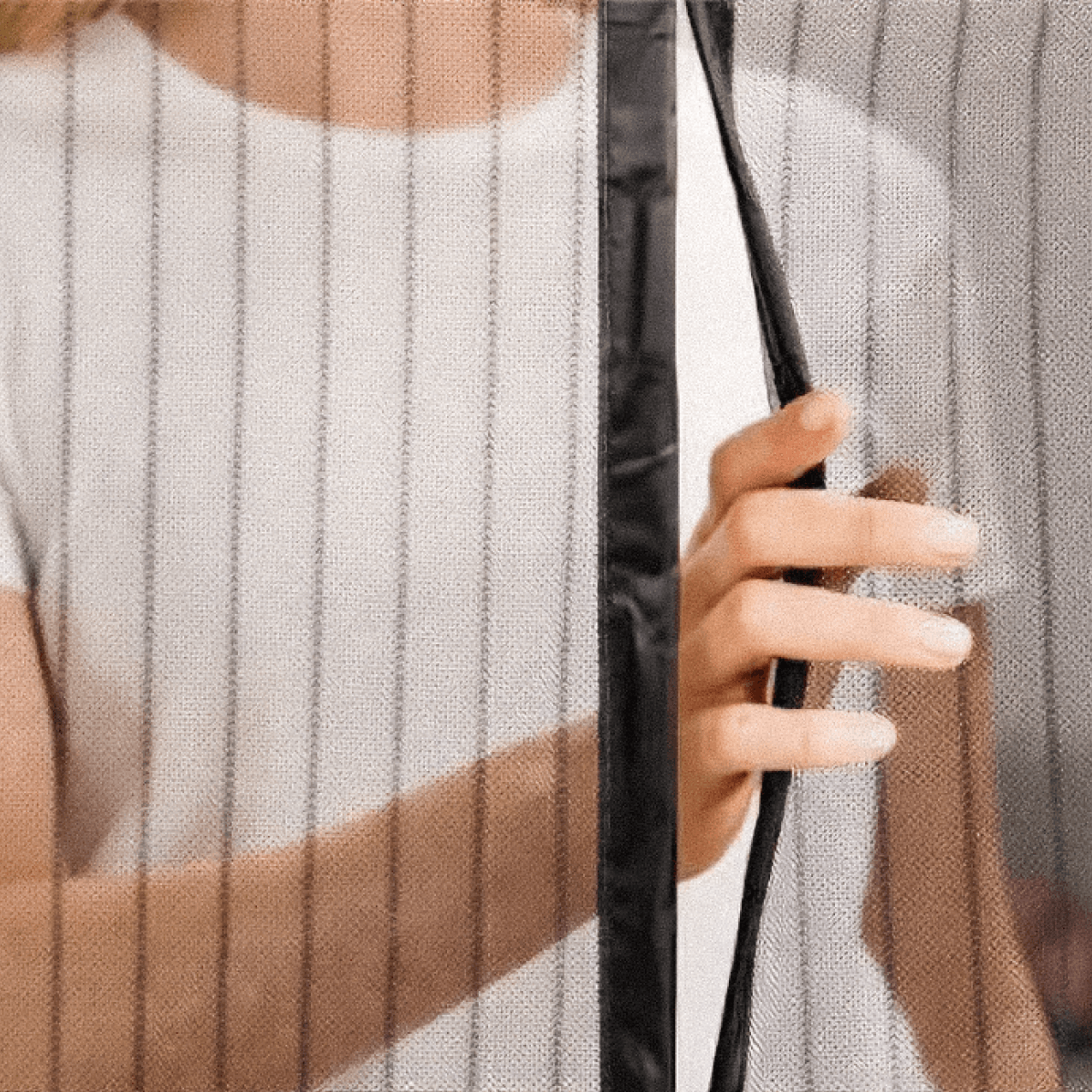 Close-up of a hand opening the centre magnetic closure between two mesh screen door panels